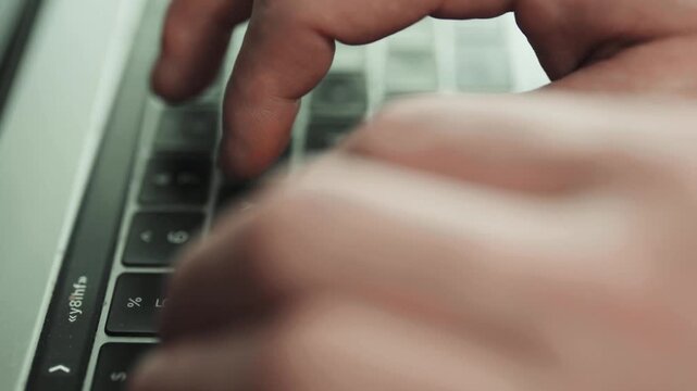  Hands typing on laptop keyboard on clean white desk.