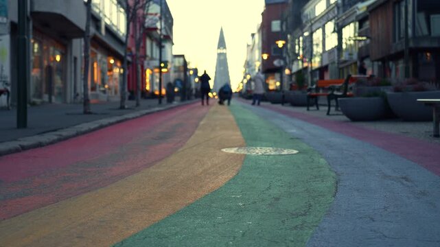 Close up of rainbow painted street in a European city at sunrise with church in soft bokeh background.