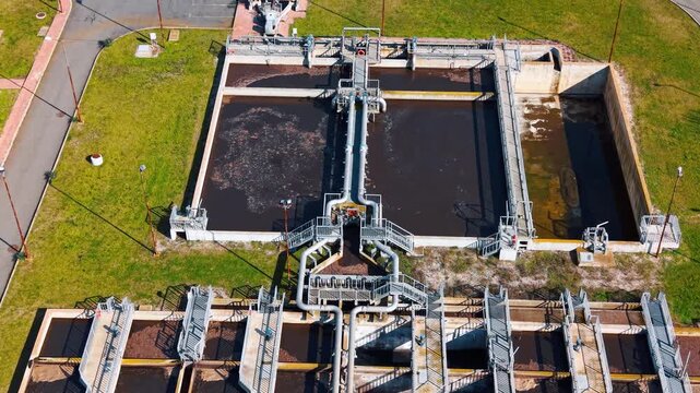 High angle shot of rectangular sludge treatment basins. Aerial view of primary treatment tanks with piping system and mechanical equipment.
