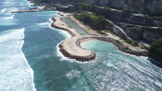 Cinematic aerial drone orbit left around coastal rock formation at Green Bowl Beach, Bali, Indonesia.