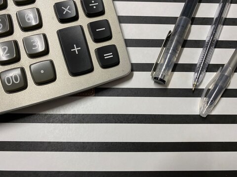 Concept of financial stress, tax problems, or business frustration. Office equipment on a black and white striped surface representing struggle and problem-solving.