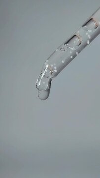 Beauty serum liquid dripping from the tip of the serum pipette