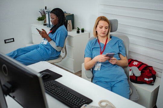 Nurses scrolling on smartphones ignoring work in office