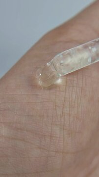 Liquid serum dripping onto the hand. Close up view for the concept of beauty.