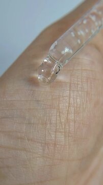 Liquid dripping onto the hand with a serum pipette. Close up view for the concept of beauty.