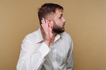Obraz premium Man with a curious expression leaning in to listen in a warm-toned setting during a quiet afternoon