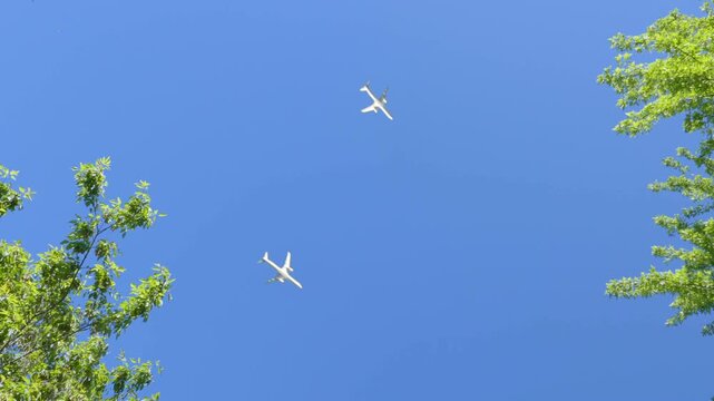 Commercial jets crossing the skies, planes or air traffic. Multiple aircraft passing above against blue sky.
