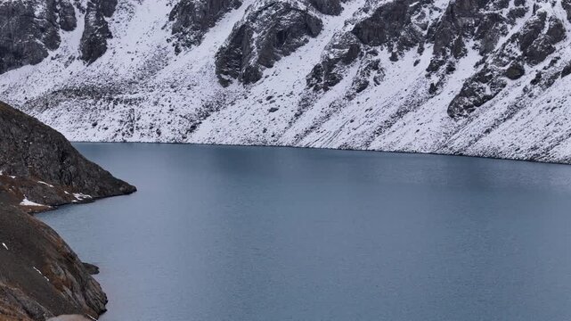 Hiker Sitting Above Alpine Lake in Winter Drone View