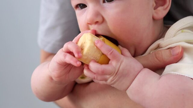  A baby picking and eating food from a sectioned plate with her fingers. The concept of weaning is based on the principle of "child-choosing food," independent feeding, healthy breakfast, and fine mot