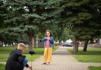 Fototapeta premium Girl and boy teenager bloggers influencer records videos from the blog on a smartphone outdoor.