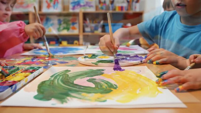 Children engaging in creative painting activity using brushes and colorful paints in a classroom setting