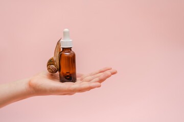 Cosmetic brown bottle with snail in elegant hand. Concept of skin care product, spa, luxury, natural beauty © Antonio
