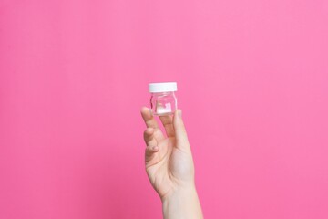 Hand holding small empty glass jar with lid