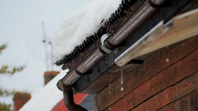 water dripping from a gutter and roof covered in melting snow 180fps slow motion. A detailed seasonal sequence showing the transition from winter to spring, featuring snow runoff and water droplets