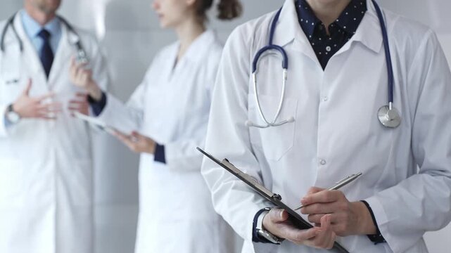 Medical professional writing on clipboard with stethoscope, a doctor and female assistant collaborating in a clinic, discussing patient data and healthcare information