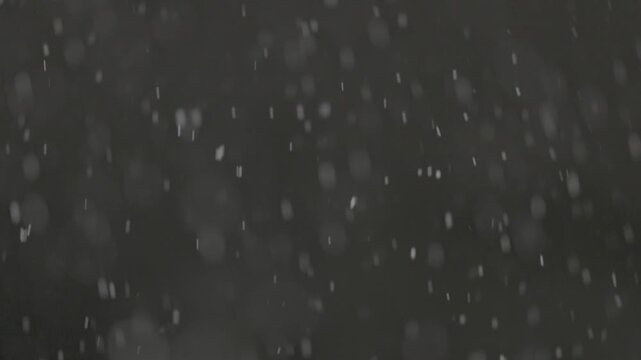 Slow motion falling snow particles on dark background, cinematic winter atmosphere with dense blizzard effect, swirling flakes, bokeh for overlays. ProRes 422, 10 bit ungraded C-LOG2, Slow motion vide