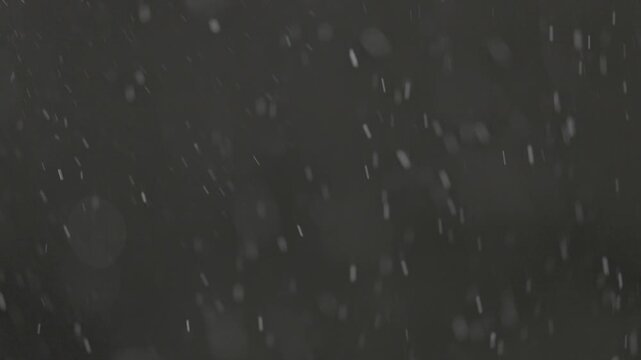Slow motion falling snow particles on dark background, cinematic winter atmosphere with dense blizzard effect, swirling flakes, bokeh for overlays. ProRes 422, 10 bit ungraded C-LOG2, Slow motion vide