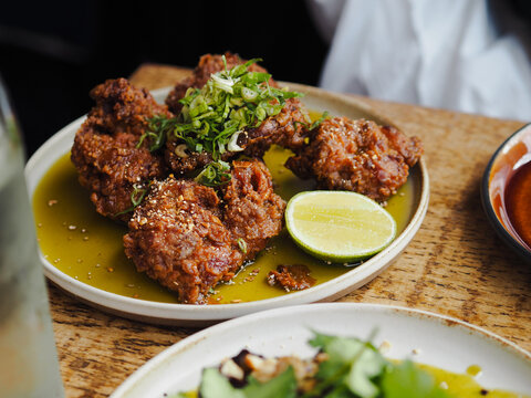 Poulet frit croustillant avec oignons verts et citron vert au curry, servie dans une assiette au restaurant