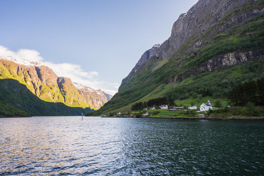Traditional white church and houses in a small village nestled along the deep blue waters of a majestic Norwegian fjord.