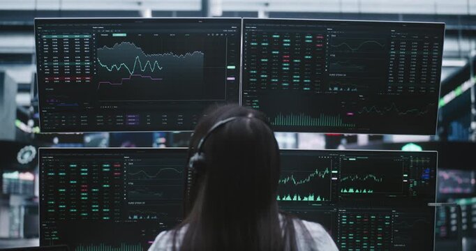 Focused Female Broker Monitoring Global Stock Exchange Indices on Multiple Digital Displays. Concept of Technical Expertise and Intensive Nature of Modern Day Trading From Modern Private Workspaces.