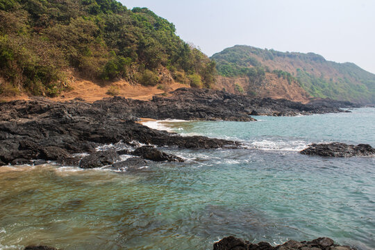 Rocky Shoreline With Soft Waves Near Coastal Hills At Nivati Beach in Maharashtra, India