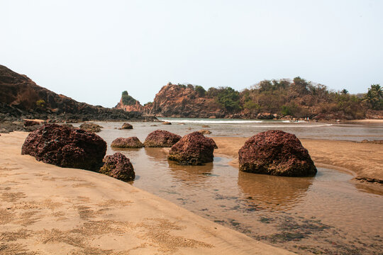 Series of Large Rocks Standing in Shallow Beach Water At Nivati Beach in Maharashtra, India