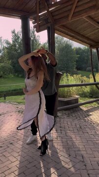 Beautiful multiethnic couple dancing during golden hour in green park. Backlit dancers in romantic embrace outdoors, sunset glow, summer love, lifestyle