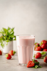 Glass of fresh strawberry milkshake, smoothie and fresh strawberries on light background. Healthy food and drink concept.