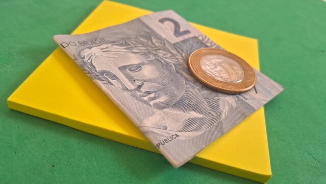 Brazilian currency note and coin on yellow background