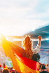 Obraz premium Young Germany woman fan stands in stadium, arms raised high, holding Germany flag, embodying national pride and sports enthusiasm under sunset skies of eventful game day. Concept of sport competitions