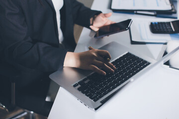 Auditors collaborating in modern office, analyzing financial documents and using calculator with a laptop displaying charts. Audit and taxes in business