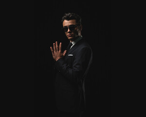Obraz premium Confident man in suit with sunglasses posing with joined hands