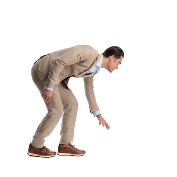 Side view of curious man in linen suit reaching down