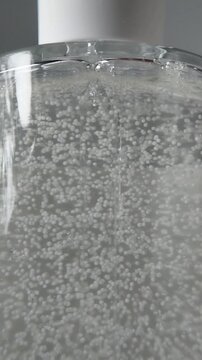 Clear bottle of beauty serum up close. Natural serum. Liquid bubbles inside the packaging.