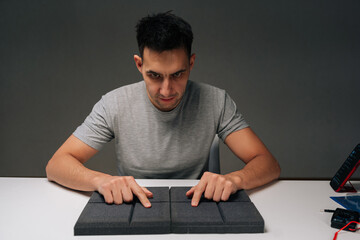 Portrait of man touching soundproof acoustic foam panels sitting at white desk, evaluating material...