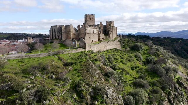 Aerial view of Belv&iacute;s de Monroy Castle, a medieval hilltop fortress ruins overlooking rural Caceres landscape, historic defensive architecture surrounded by countryside and open skies.