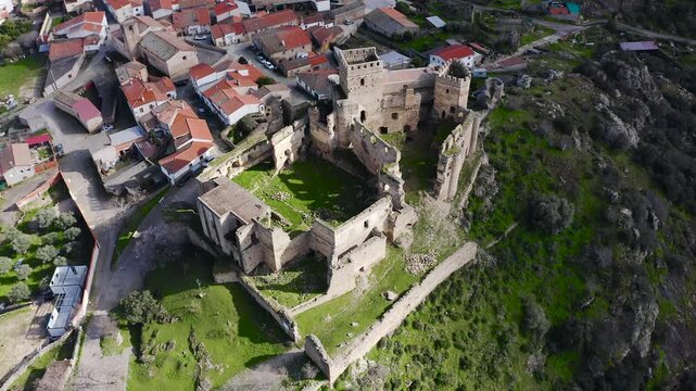 Aerial view of Belv&iacute;s de Monroy Castle, a medieval hilltop fortress ruins overlooking rural Caceres landscape, historic defensive architecture surrounded by countryside and open skies.