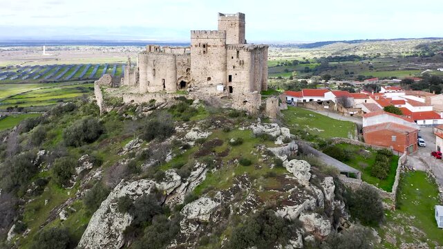 Aerial view of Belv&iacute;s de Monroy Castle, a medieval hilltop fortress ruins overlooking rural Caceres landscape, historic defensive architecture surrounded by countryside and open skies.