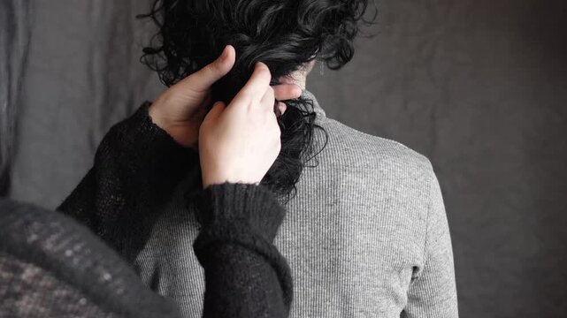 woman braids a braid on black curly hair. back view. hairdressing services, well-groomed healthy hair, curls, biowave, hair styling, advertising and hairdressing services of a beauty salon