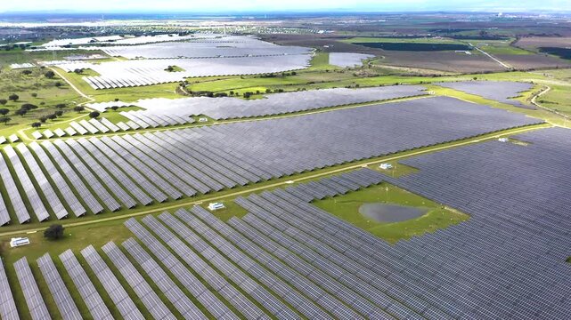 View of large solar power plant near Belv&iacute;s de Monroy Castle in C&aacute;ceres, Spain. Vast photovoltaic panels covering rural landscape, renewable energy infrastructure in Extremadura countryside.