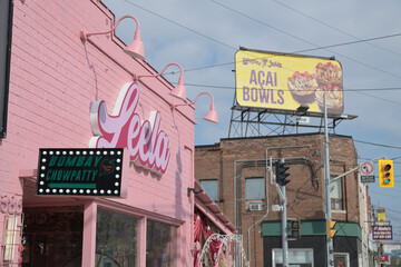 Naklejka premium looking east on Gerrard St E with view of Leela Indian Food Bar at 1386 Gerrard St E, rooftop Booster Juice billboard, and buildings, Toronto