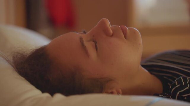 Relaxed hotel repose. Woman resting quietly in hotel setting. Serene profile of woman in tranquil hotel environment. Closeup of woman peacefully lying down with closed eyes in quiet hotel room