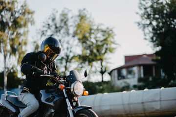 A male motorcyclist wearing a helmet on a city motorcycle in the city in summer