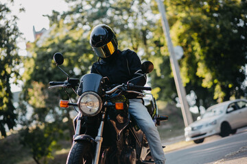A male motorcyclist wearing a helmet on a city motorcycle in the city in summer
