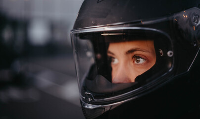 A female motorcyclist riding a motorcycle in the city in the evening