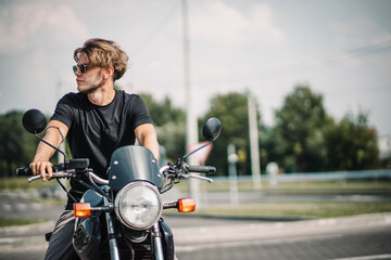 A man motorcyclist wearing sunglasses in the city in summer on a motorcycle