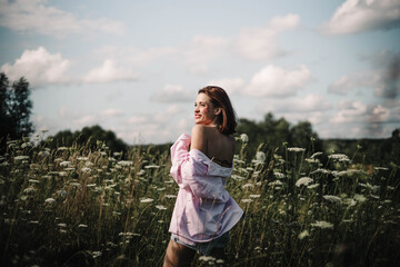 A woman walks through a field of tall grass in summer