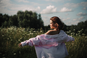 A woman walks through a field of tall grass in summer