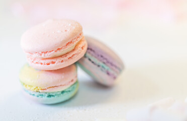 Obraz premium Three gourmet macarons arranged casually on clean surface. Smooth textured shells and rich filling visible. Sweet confection concept with soft bokeh backdrop.