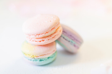 Fototapeta premium Colorful macarons in pink, mint and lavender tones. Delicate sandwich cookies with cream layer. Elegant bakery treat styled in minimal pastel setting.